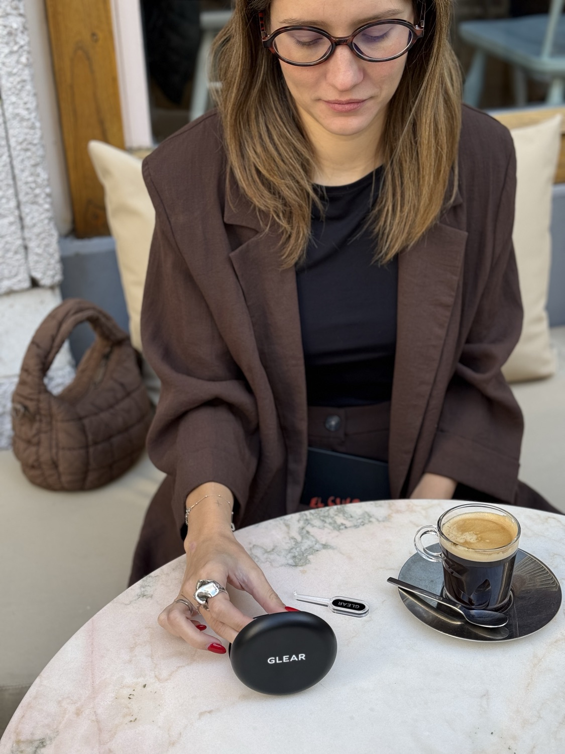 Una paciente con el estuche GLEAR y un café, en la mesa de un bar