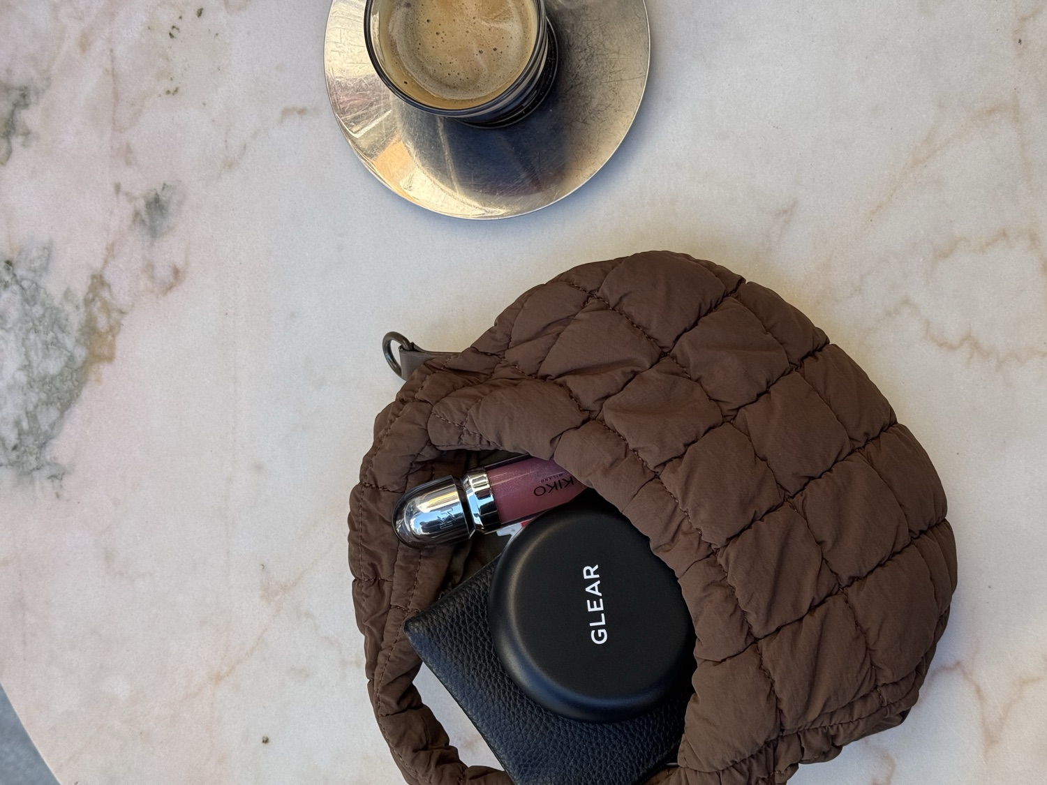 El bolso con el estuche GLEAR y el café sobre la mesa